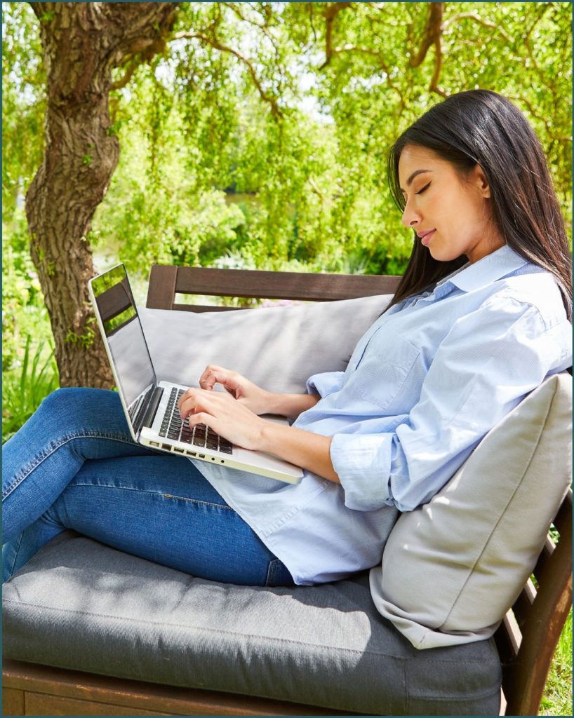 woman sitting outdoors with a laptop in her lap
