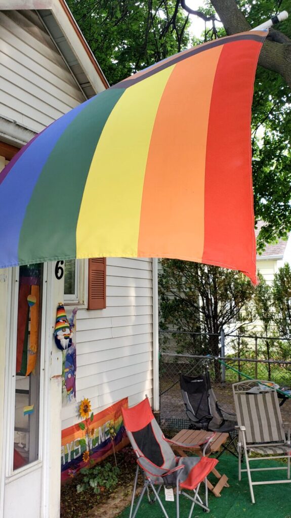 A large rainbow flag flies outside a porch